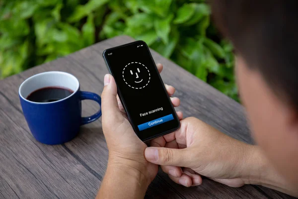 Mani maschili che tengono il telefono con la scansione del volto ID sullo schermo — Foto Stock