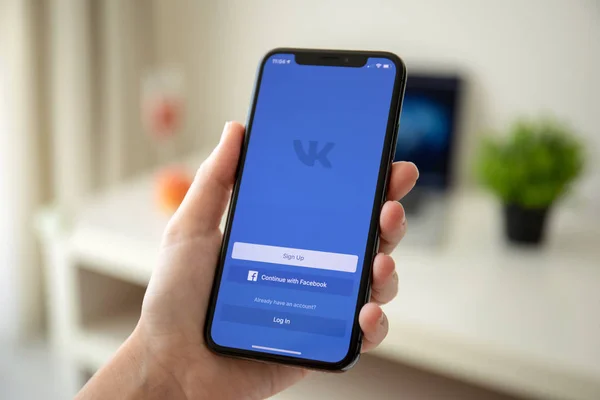 Женщина держит iPhone X с социальной сетью VK — стоковое фото