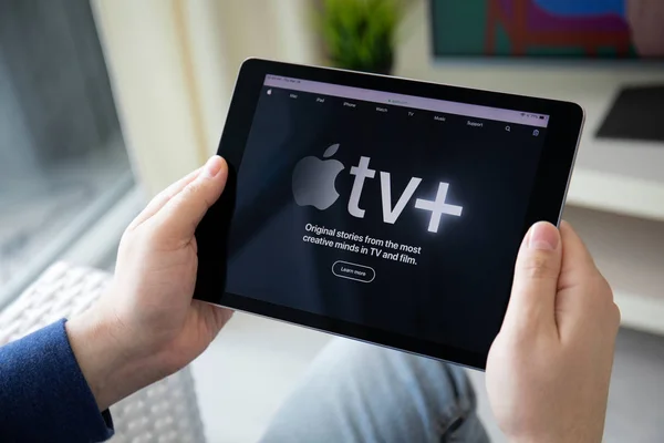 Чоловік тримає ipad з Apple Tv додаток забезпечує потокову фільми. — стокове фото