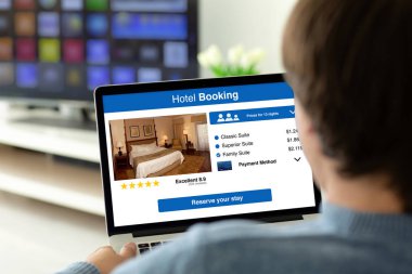 ekranda uygulama otel rezervasyonu ile dizüstü bilgisayar tutan adam