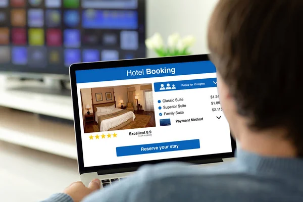 Ekranda uygulama otel rezervasyonu ile dizüstü bilgisayar tutan adam — Stok fotoğraf