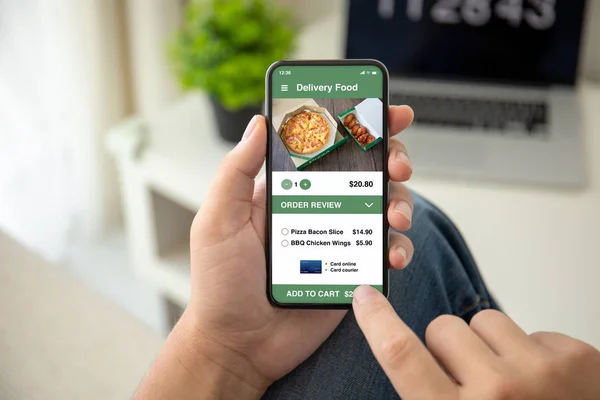 Мужчина держит в руках телефон с приложением доставки еды на экране — стоковое фото