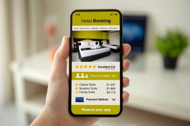 ekranda uygulama otel rezervasyonu ile telefon tutan kadın eller