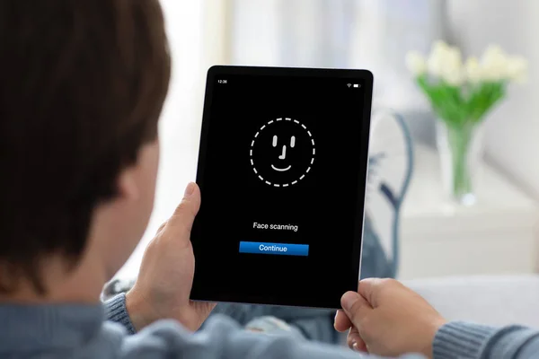 Hombre manos sosteniendo la tableta del ordenador con la cara ID escaneo — Foto de Stock