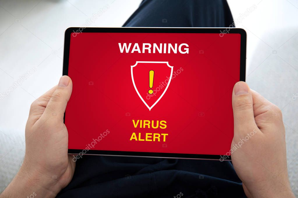 man hands holding computer tablet with warning virus alert 