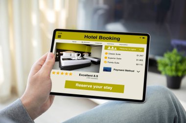 uygulama otel rezervasyonu ile bilgisayar tablettutan adam elleri