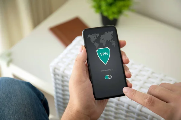 Mann hält Handy mit App vpn privates Netzwerk im Zimmer — Stockfoto