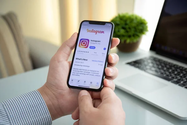 Man hand holding iPhone X with social networking service Instagr — Stock Photo, Image