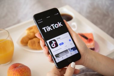 Ekranda Tiktok ile iphone 8 Plus tutan kadın.