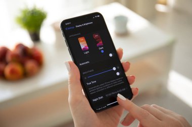 Ios13 ve Dark Mode ile iphone X tutan kadın el.
