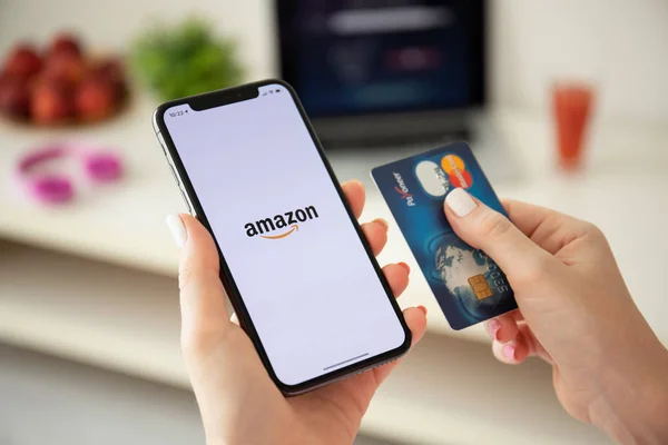 Woman holding iPhone X with Internet shopping service Amazon — Stock Photo, Image