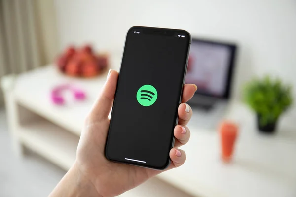 Женщина держит iPhone X с музыкальным сервисом Spotify на экране — стоковое фото