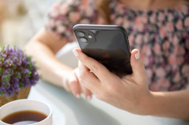 Apple iPhone 11 'i tutan ve masada oturan kadın.