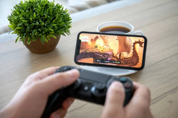 Человек, держащий в руках игру Dualshock Rayman на экране iPhone 11 . — стоковое фото
