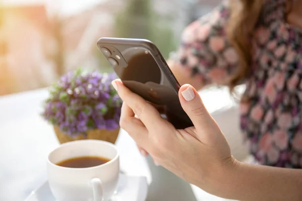 Kvinnlig hand håller Apple iphone 11 och sitter vid bordet — Stockfoto