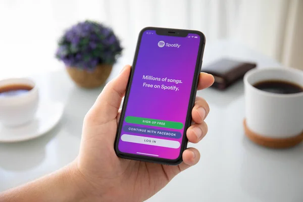 Мужчина держит iPhone 11 с музыкальным сервисом Spotify — стоковое фото