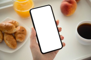 Kahvaltıda kafede telefon tutan bir kadın.