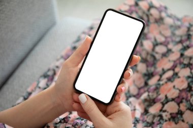 Çok renkli elbiseli bir kadın telefonu kapalı ekranda tutuyor.