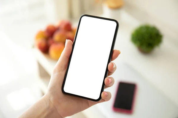 Female hand holding phone with isolated screen in room — ストック写真