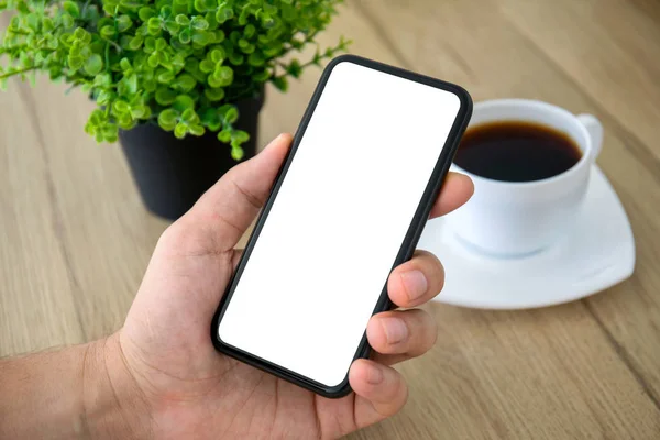 Male hand holding phone isolated screen over table in cafe — ストック写真