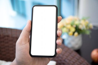 Erkek eli telefonu evde tek başına tutuyor.