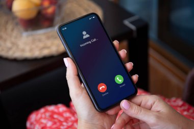 Kırmızı elbiseli kadın elleri, gelen aramalarla birlikte telefonu tutuyor.