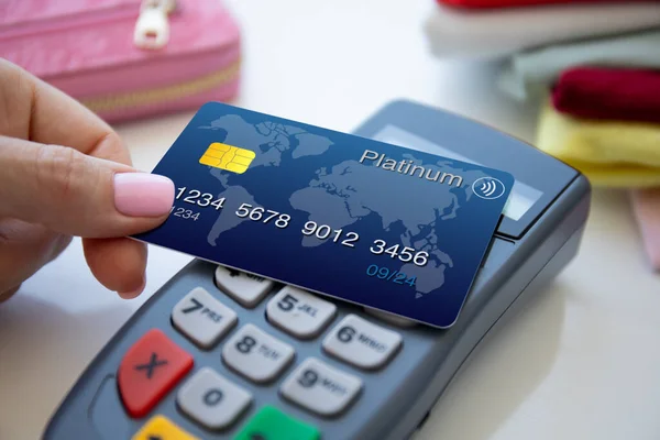 woman hand holding plastic card and pay pass online terminal in the store