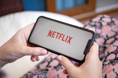 Alanya, Türkiye - 8 Haziran 2020: iPhone 11 'i çok uluslu eğlence şirketi Netflix ile elinde tutan kadın ekranda medya ve video sunuyor.