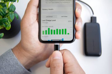 Alanya, Türkiye - 28 Mayıs 2020: Powerbank RavPower ve iPhone 11 ile el ele tutuşan adam ekranda Pil uygulaması.