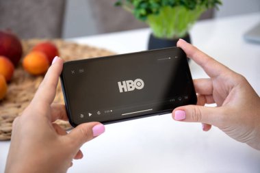 Alanya, Türkiye - 3 Temmuz 2020: Apple iPhone 11 'i çok uluslu eğlence şirketi HBO ile el ele tutuşan kadın ekranda medya ve video sunuyor