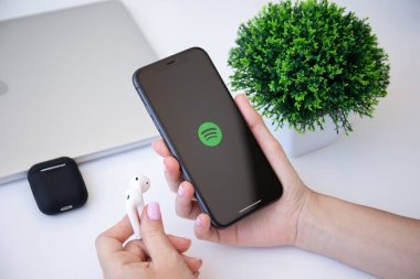 Alanya, Türkiye - 3 Temmuz 2020: iPhone 11 'i tutan kadın ve müzik hizmeti Spotify ekranda. iPhone 11 Apple tarafından oluşturuldu ve geliştirildi..
