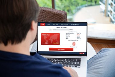 Adam evdeki bilgisayar bilgisayarında online alışveriş uygulaması kullanıyor.