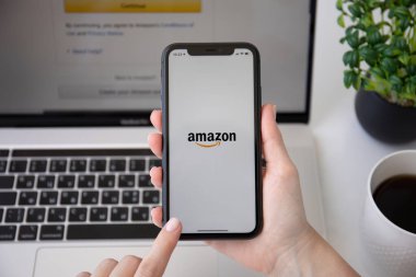 Alanya, Türkiye - 7 Haziran 2020: Kadın eli iPhone 11 ve Macbook Pro ile çevrimiçi İnternet alışveriş servisi Amazon ekranda.