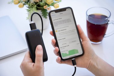 Alanya, Türkiye - 6 Haziran 2020: Powerbank RavPower ve iPhone 11 uygulamalı kadın el ele tutuşması ekranda Batarya