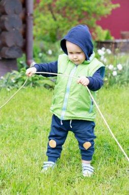 Çelik yelek ve kapüşonlu bir çocuk, yeşil bir arka plana elektrik teli geriyor.