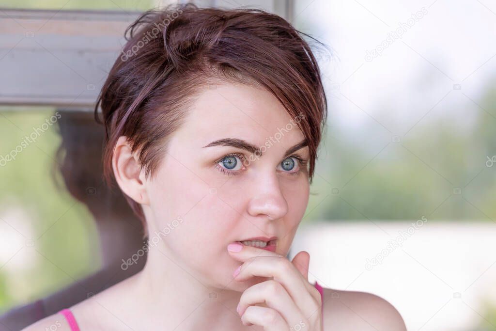 The girl who is thinking about something thoughtfully touches her lips with her hand