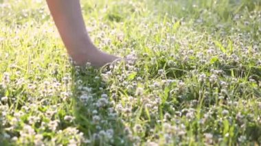 Çimenlerde yalın ayak yürüyen bir kadının ayakları.