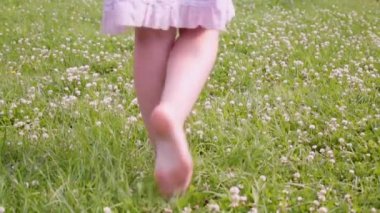 Çimenlerde yalın ayak yürüyen bir kadının ayakları.