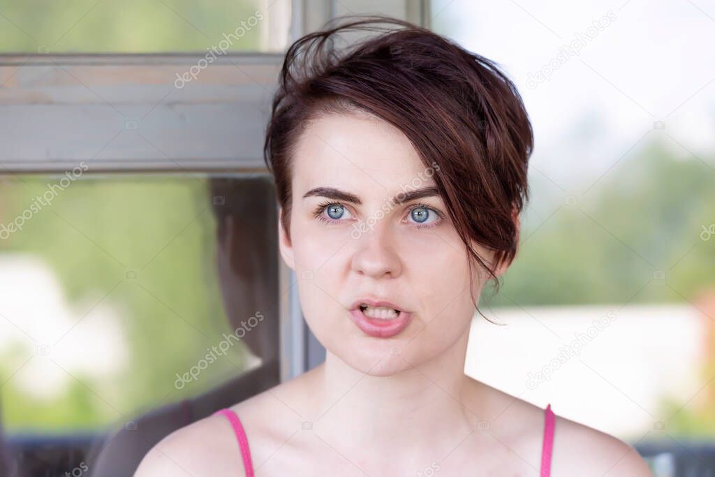 Portrait of an angry blue-eyed brunette saying something to someone