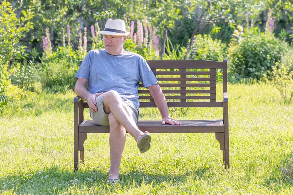 Een ongeschoren man zit op een parkbank. Rechtenvrije Stockfoto's