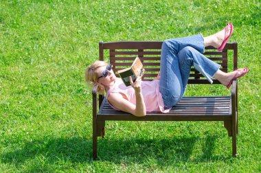 Kadın kitap ile dinleniyor, yukarıdaki bankta.