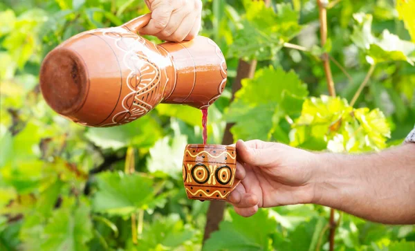 Primo piano delle mani con brocca e tazza di vino — Foto Stock