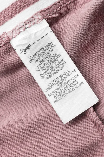 Etiqueta Ropa Composición Cuidado Sobre Fondo Textil Rosa Primer Plano — Foto de Stock