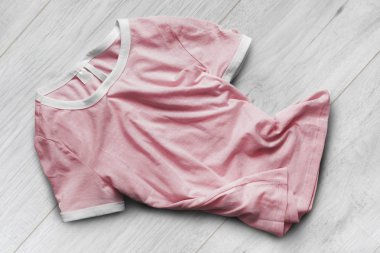 Beyaz ahşap zemin üzerinde buruşuk pembe temel t-shirt