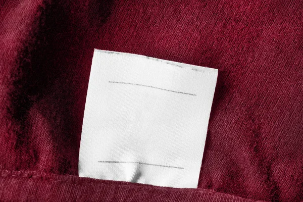Etiqueta Ropa Blanca Blanco Sobre Fondo Textil Rojo Primer Plano —  Fotos de Stock