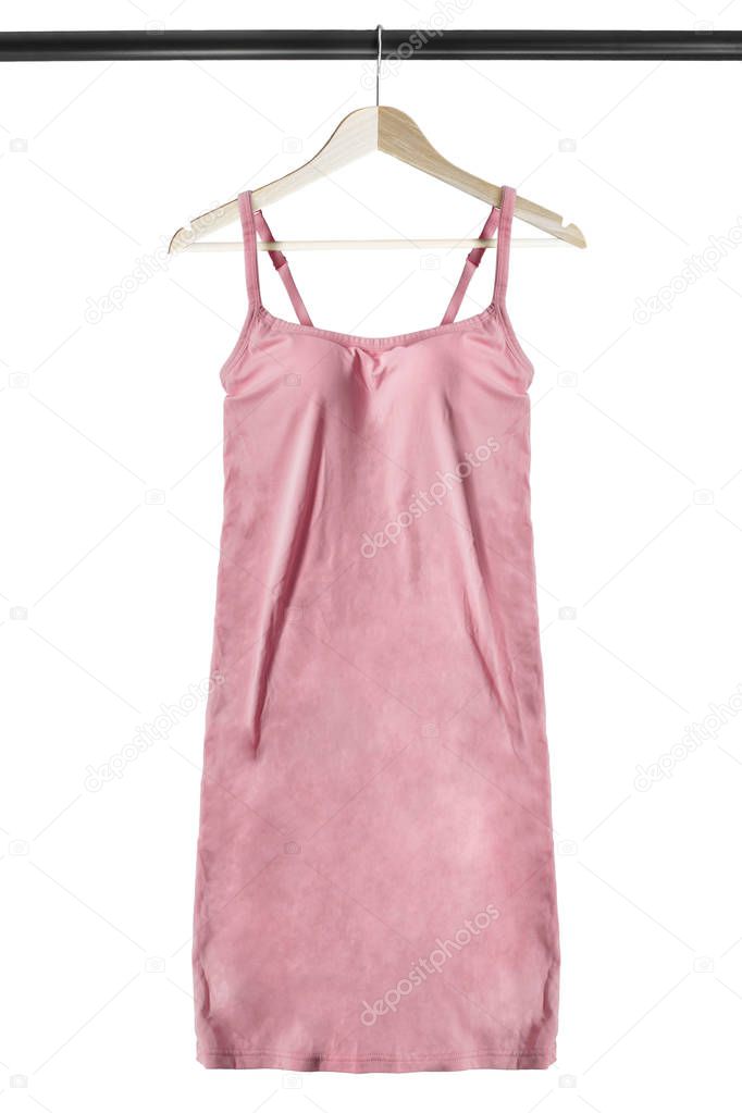 Pink silk dress on shoulder straps hanging on wooden clothes rack isolated over white