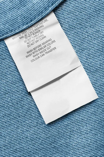 Cuidado Etiqueta Ropa Primer Plano Sobre Fondo Textil Azul — Foto de Stock