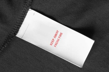 Giysi etiketi yangın uzak tutmak siyah tekstil arka plan portre üzerinde diyor.