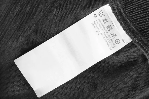 黒い繊維の背景のクローズ アップの介護服ラベル — ストック写真