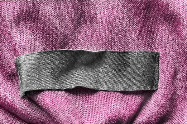 黑色纺织服装标签粉红色纺织品背景特写 — 图库照片